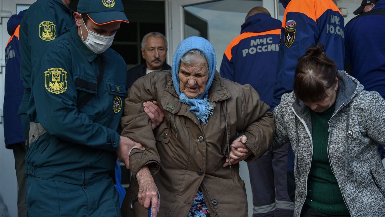 A lakosság evakuálását végző orosz mentőalakulatok tagjai az idősek otthonának egyik lakóját kísérik Herszon ukrán kikötővárosban, a Krímtől északnyugatra 2022. november 5-én.