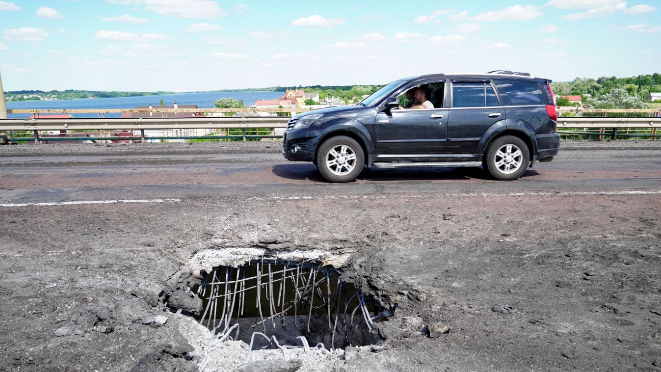  picture taken on July 21, 2022 shows a car moving past a crater on Kherson's Antonovsky (Antonivskiy) bridge across the Dnipro river caused by a Ukrainian rocket strike, amid the ongoing Russian military action in Ukraine.