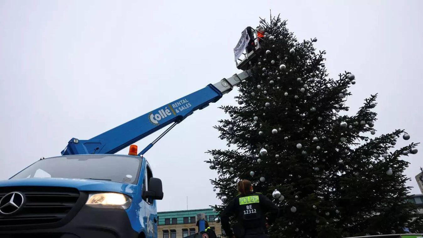 Klímaaktivisták csonkítják meg a berlini karácsonyfa tetejét a rendőrök szeme láttára 2022.12.21-én. (Forrás: MegaNews Updates / Twitter)