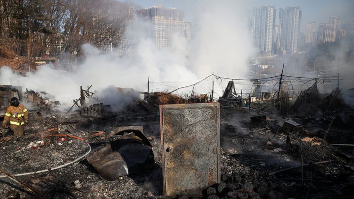 Firefighters work at the scene of a fire at Guryong village, in Seoul