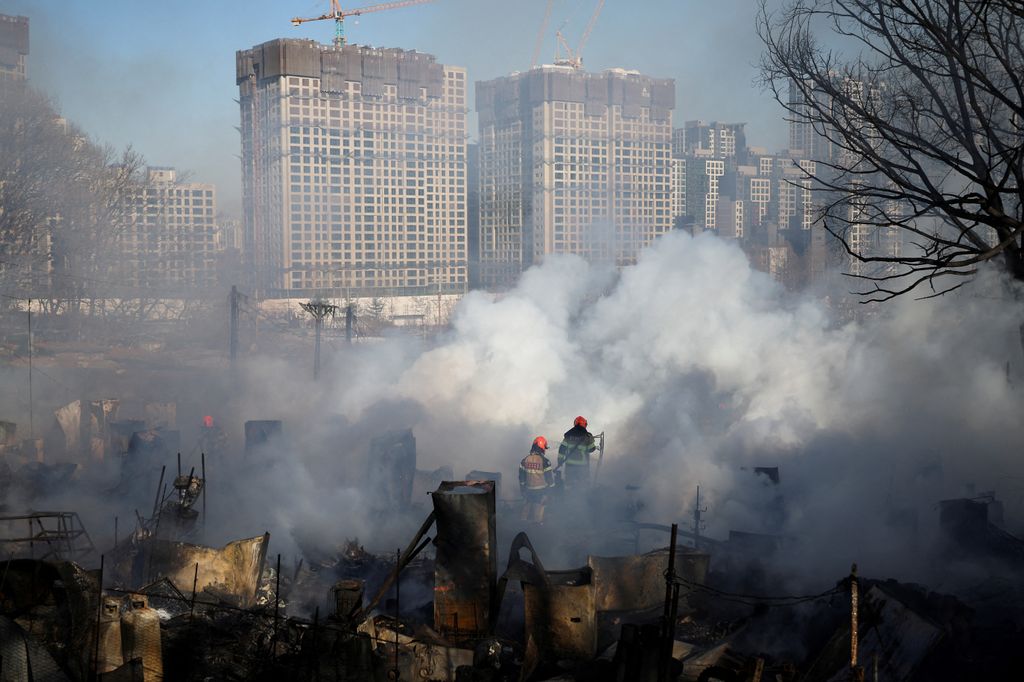 Firefighters work at the scene of a fire at Guryong village, in Seoul