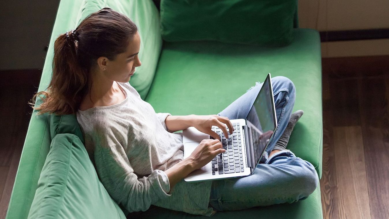 Relaxed,Woman,Using,Laptop,Sitting,On,Sofa,,Millennial,Girl,Checking