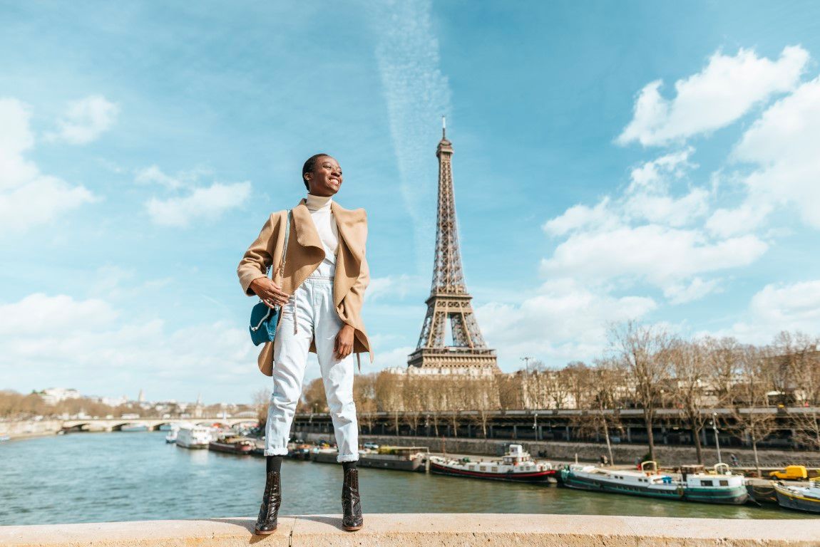 France, Paris, Smiling woman standing on a bridge with the Eiffel tower in the background