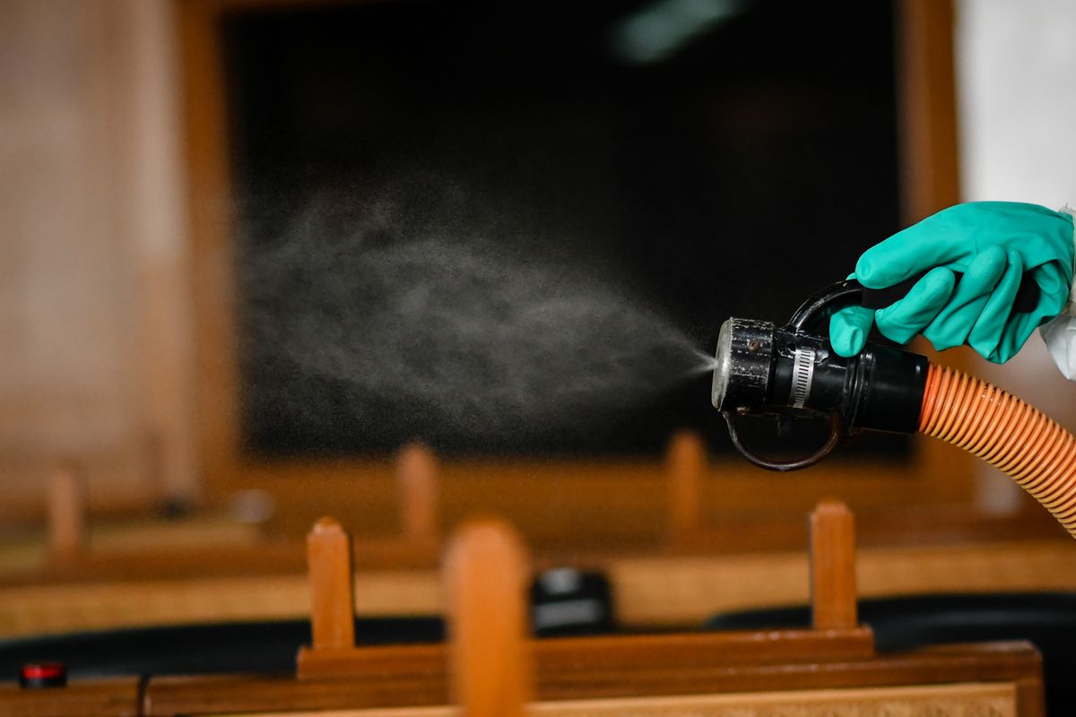 A Thai cleaner sprays disinfectant inside a meeting room as