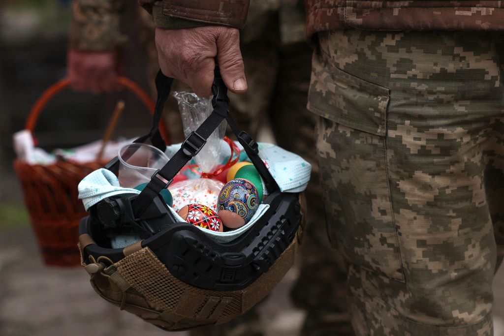 Ukrán katona vár áldásra rohamsisakjában hagyományos ünnepi ételekkel az ortodox húsvéton, április 15. Fotó: AFP/Anatolij Sztyepanov