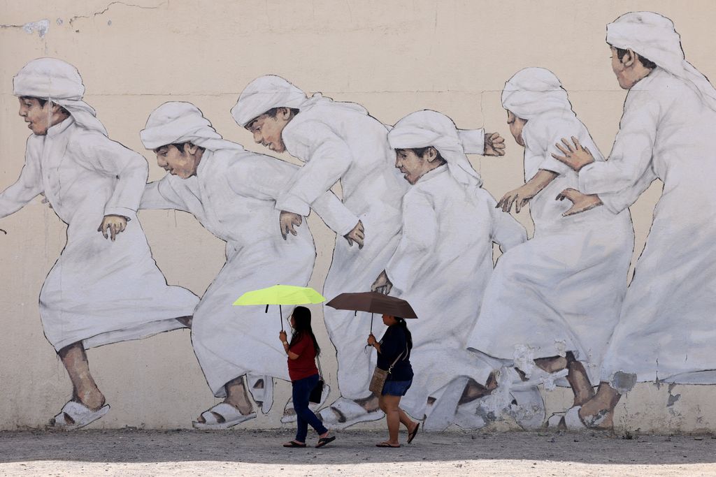 Dubaji asszonyok sétálnak gyerekeket ábrázoló falkép előtt, április 15. Fotó: AFP/Karim Sahib