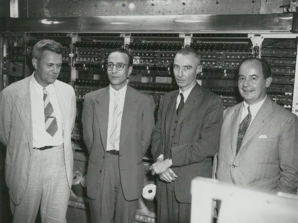 Neumann János (jobb szélen) princetoni tudóstársaival, köztük az atombomba atyjaként emlegetett Robert Oppenheimerrel (j2) az 1950-es években. Háttérben az ősszámítógép, a MANIAC