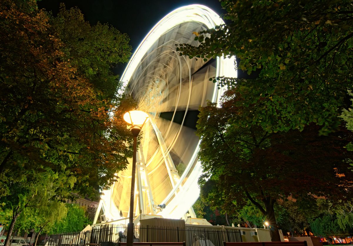 Big ferris wheel (Budapest Eye) at city park. Budapest Eye at night. Tree Leaves Border. Natural Frame. Colorful light trails with motion blur effect, long time exposure. Budapest, Hungary
Lugas