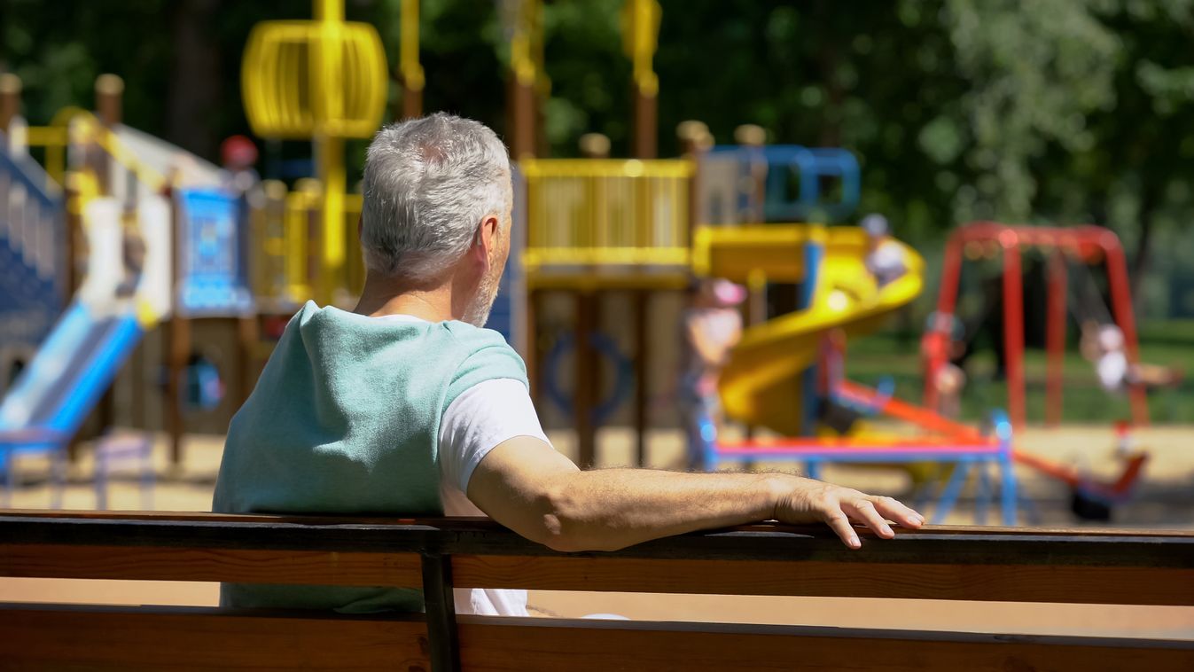 Male,Pensioner,Sitting,On,Bench,And,Watching,Grandkids,On,Playground,