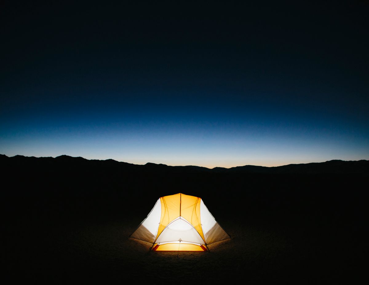 Illuminated camping tent in vast desert at dusk, Black Rock Desert, Nevada