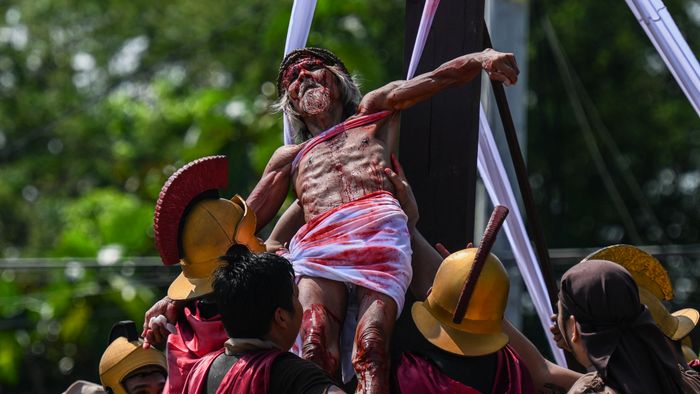Philippine Christian devotee Wilfredo Salvador (C) takes part in the re-enactment of the crucifixion of Jesus Christ on Good Friday in San Fernando, Pampanga province on March 29, 2024. (Photo by JAM STA ROSA / AFP)