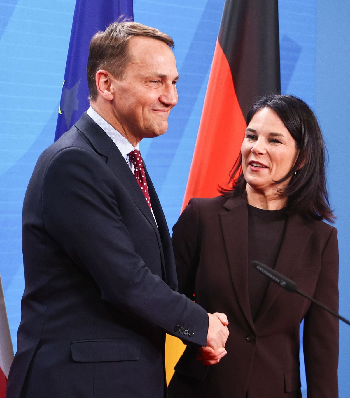 Annalena Baerbock német külügyminiszter és lengyel hivatali partnere, Radoslaw Sikorski kezet fog közös sajtóértekezletük után Berlinben