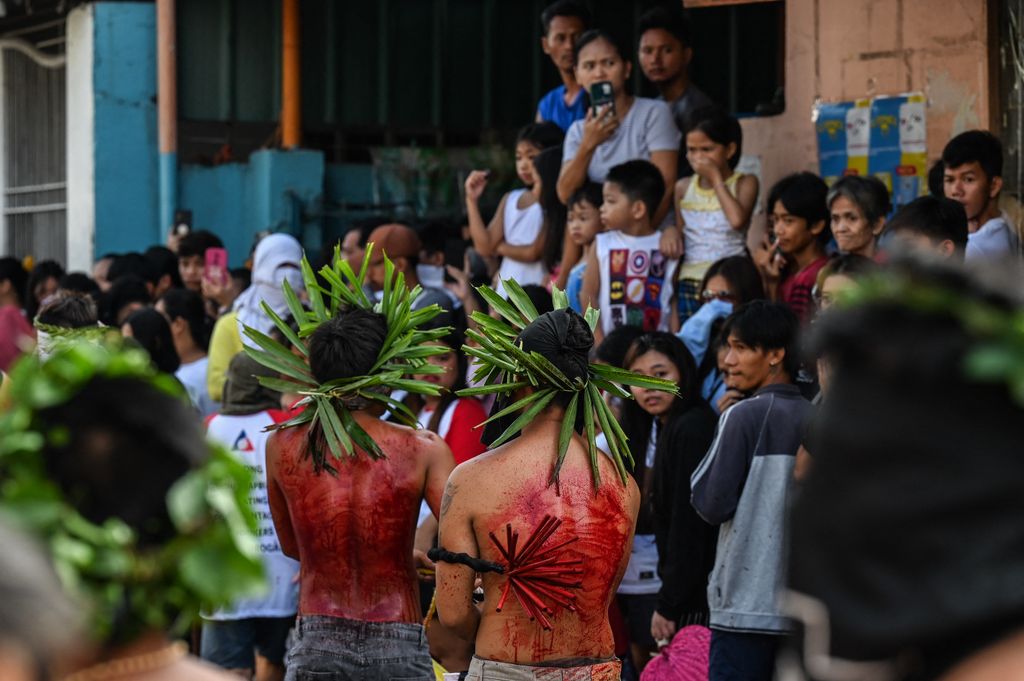 People watch as penitents flagellate themselves during Good Friday as part of Holy Week celebrations in San Fernando, Pampanga province on March 29, 2024. (Photo by JAM STA ROSA / AFP)