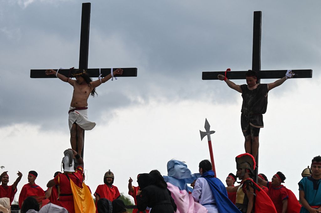 Philippine Christian devotee Ruben Enaje (L) performs his 35th re-enactment of the crucifixion of Jesus Christ on Good Friday in San Fernando, Pampanga province on March 29, 2024. (Photo by JAM STA ROSA / AFP)