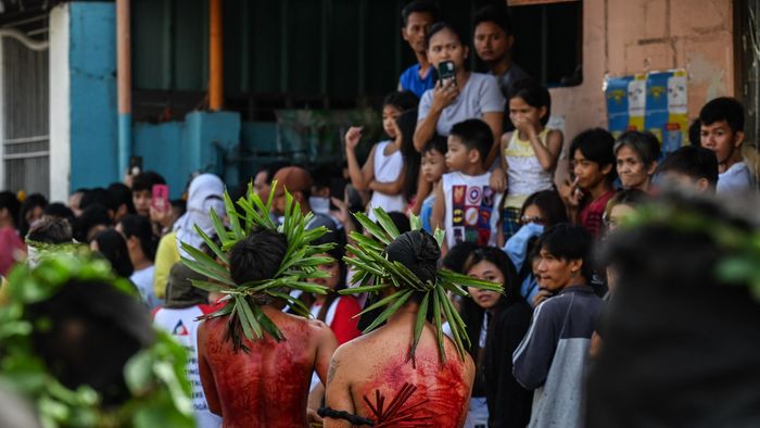 People watch as penitents flagellate themselves during Good Friday as part of Holy Week celebrations in San Fernando, Pampanga province on March 29, 2024. (Photo by JAM STA ROSA / AFP)