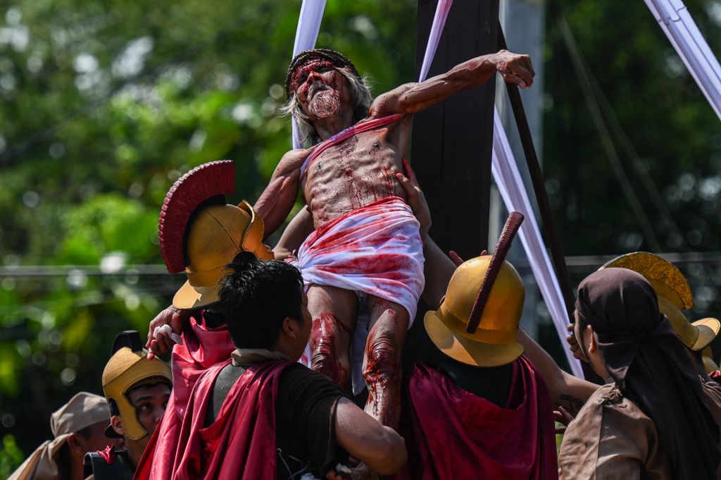 Philippine Christian devotee Wilfredo Salvador (C) takes part in the re-enactment of the crucifixion of Jesus Christ on Good Friday in San Fernando, Pampanga province on March 29, 2024. (Photo by JAM STA ROSA / AFP)
