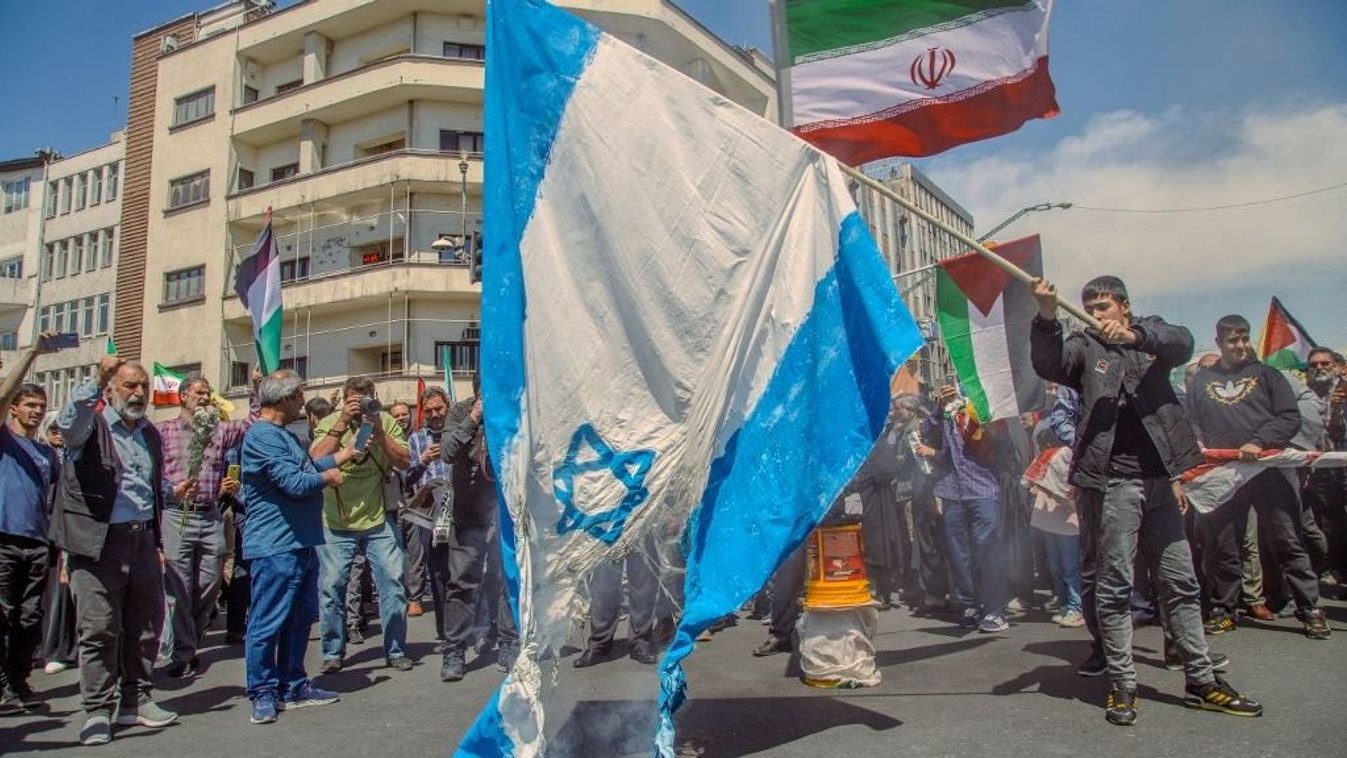 Iráni tüntetők elégetik az izraeli zászlót, miközben egyikük iráni és palesztin zászlókat lenget Teheránban, Iránban, 2024. április 5-én, pénteken. A teheráni nagygyűlésen ezrek vettek részt a gyászmenetben, amelyet annak a hét forradalmi gárdistának a gyászszertartásán tartottak, akik hétfőn meghaltak egy széles körben Izraelnek tulajdonított légicsapásban, amely lerombolta Irán konzulátusát a szíriai fővárosban.