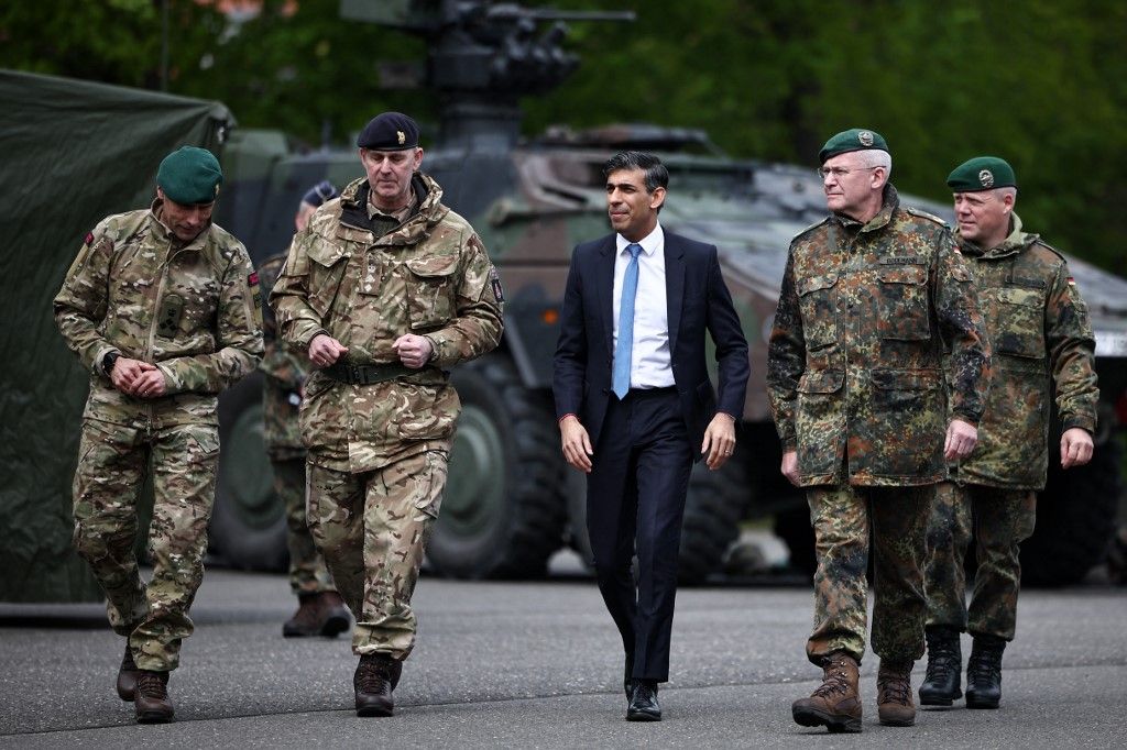 Nagy-Britannia miniszterelnöke, Rishi Sunak (C) Andre Bodemann német altábornaggyal (2ndR) és a brit csapatok katonáival sétál, miközben a berlini Julius Leber laktanyába látogat, hogy a német fővárosban április 24-én tett látogatása során csapatokkal találkozzon és hadifelszereléseket nézzen meg. (Fotó: AFP/HENRY NICHOLLS)