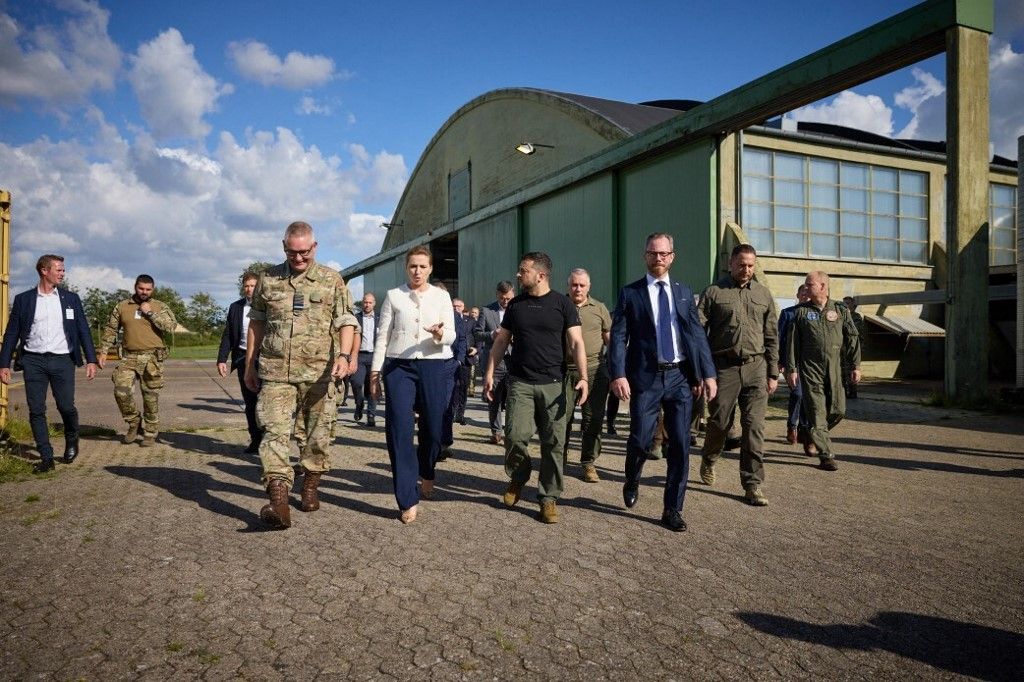 Az ukrán elnököt Mette Frederiksen  dán miniszterelnök üdvözölte a Dán Királyi Légierő Fighter Wing Skrydstrup légibázisán Koppenhágában, Dániában 2023. augusztus 21-én. A bázison tett látogatás során az államfő megvizsgálta F -16 repülőgépet, és megismerkedett azok képességeivel és működési sajátosságaival. (Fotó: Anadolu/AFP/Ukrán elnökség)