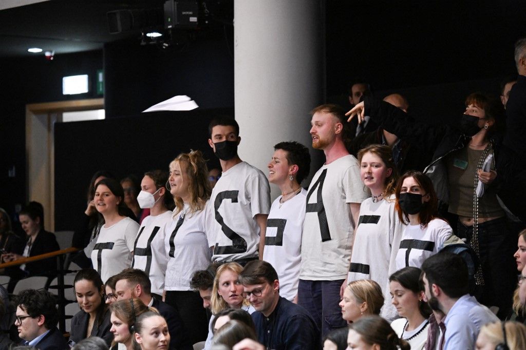 A demonstrálók ingükön „Ez a paktum öl” feliratú üzenetet viselnek a látogatói karzaton állva, miközben az Európai Parlament tagjai részt vesznek egy sor szavazáson az Európai Parlament brüsszeli plenáris ülésén 2024. április 10-én. (Fotó: AFP/JOHN THYS)