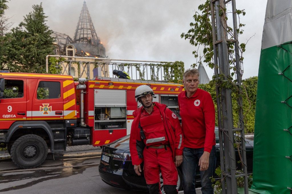 A Vöröskereszt tagjai ukrán tűzoltókkal dolgoznak együtt egy rakétatámadás következtében megsérült égő épület helyén, Odesszában 2024. április 29-én. (Fotó: Olekszandr GIMANOV / AFP)