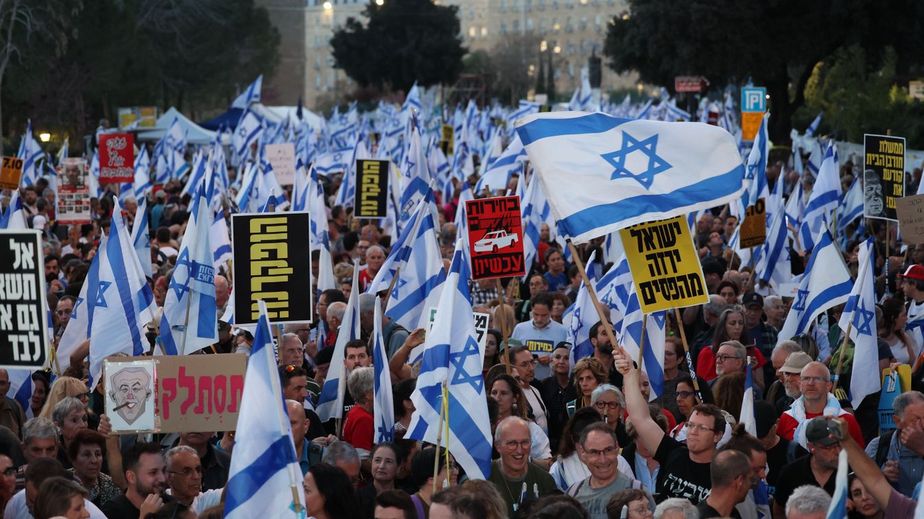 Izraeli zászlót tartó ellenzéki tüntetők követelik a Gázai övezetet irányító Hamász palesztin iszlamista szervezet által elhurcolt izraeli túszok azonnali elengedését és Benjámin Netanjahu miniszterelnök  lemondását az izraeli parlament, a kneszet előtt 2024. március 31-én. 