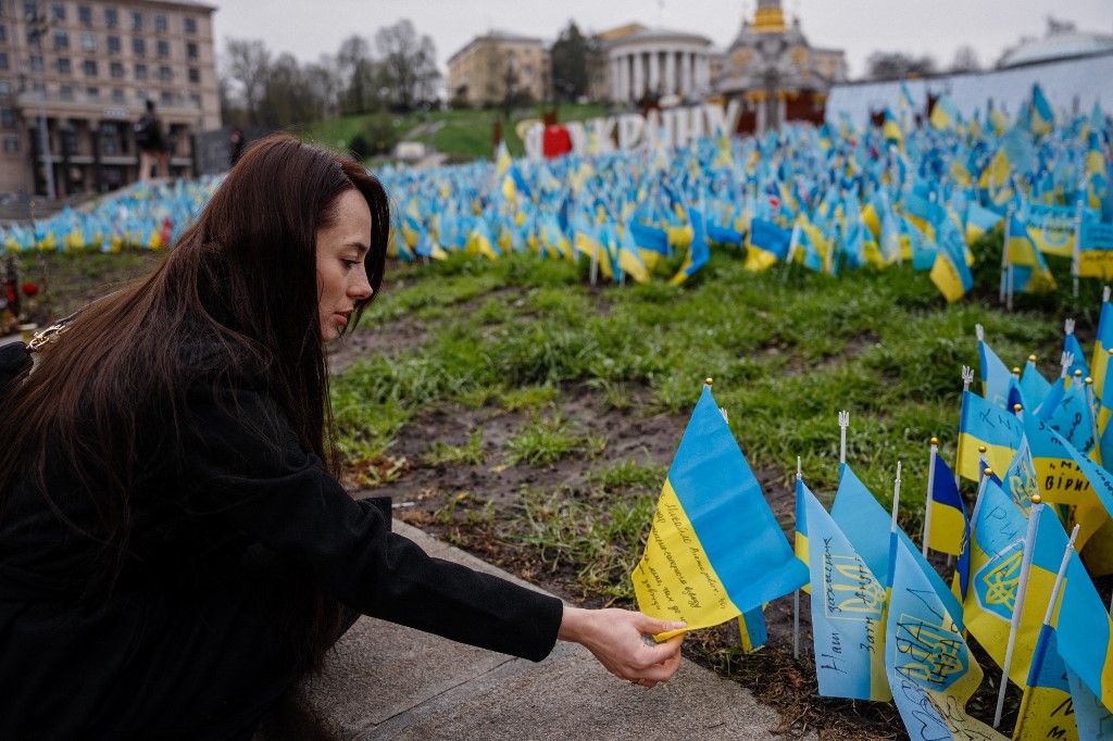 Az ukrán Olga Slyshyk zászlót helyez megölt férje emlékére a kijevi Függetlenség terén, 2023. április 13-án az Ukrajna elleni orosz invázió során meggyilkolt minden katona emlékművénél (Fotó:AFP/ Dimitar DILKOFF)