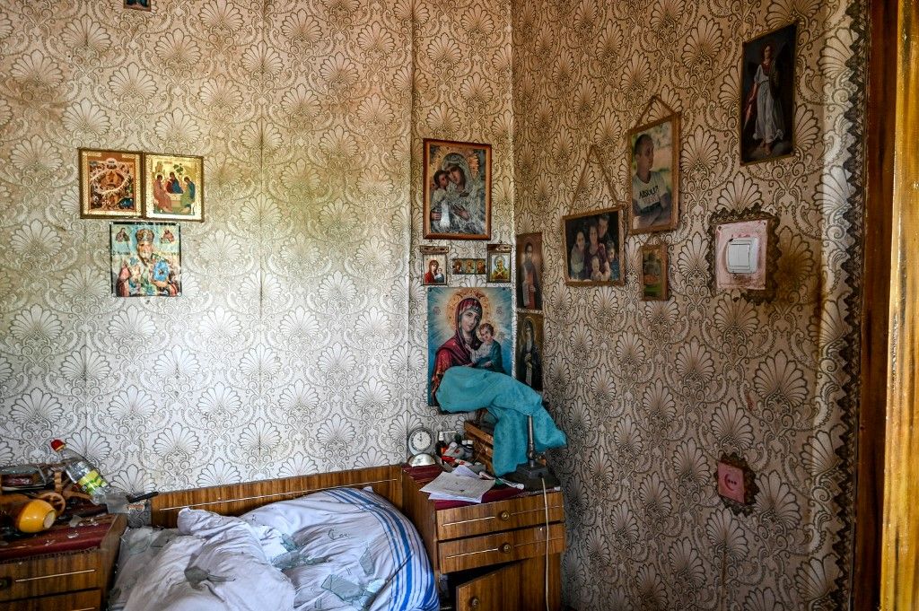 Fényképek és ikonok borítják egy orosz lövedékek által megrongálódott ház falát. (Fotó: NurPhoto/AFP/Dmytro Smolyenko)