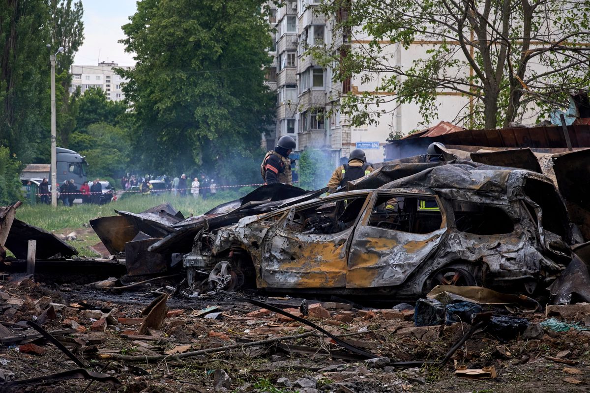 Kiégett autóroncsok mellett mentők Harkivban 2024. május 14-én, miután orosz rakéta-és siklóbomba-támadás érte a kelet-ukrajnai város egyik lakónegyedét. Világháborút hozhat, ha nyugati csapatok mennek Ukrajnába. (Fotó: MTI/EPA/Szergej Kozlov)