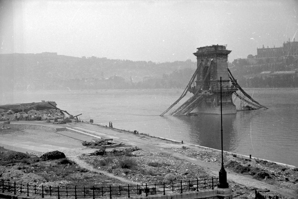 1945. Budapest V.
a lerombolt Széchenyi Lánchíd pesti hídfője, háttérben a Gellért-hegy és a romos Királyi Palota (később Budavári Palota).
Fortepan / Kurutz Márton