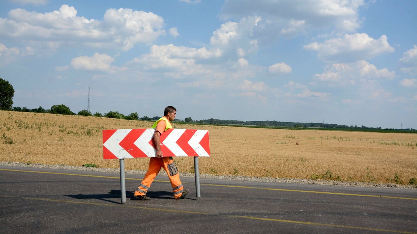 Jászfényszaru, 2015. július 1.
Egy munkás elviszi a terelõtáblát az új közúti híd felé vezetõ autóúton, Jászfényszaru határában 2015. július 1-jén. A Szolnok-Hatvan vasútvonal feletti új közúti híd a 32-es út felújítása részeként épült meg.
MTI Fotó: Mészáros János