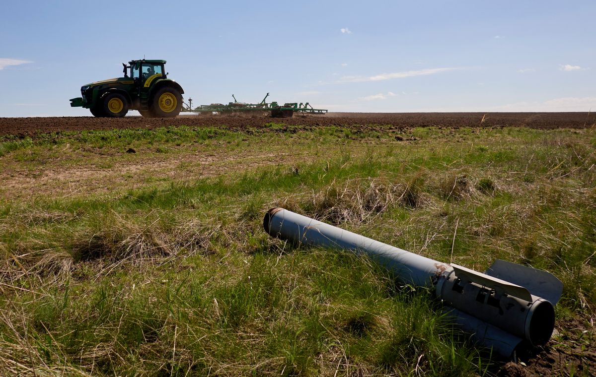Lövedékdarab közelében dolgozó traktor egy termőföldön, a Harkiv megyei Viszokopolje falu határában 2024. április 20-án. Amerika tovább folytatná a háborút, ha Bidn nyerne a választáson. (Fotó: MTI/EPA/Szergej Kozlov)