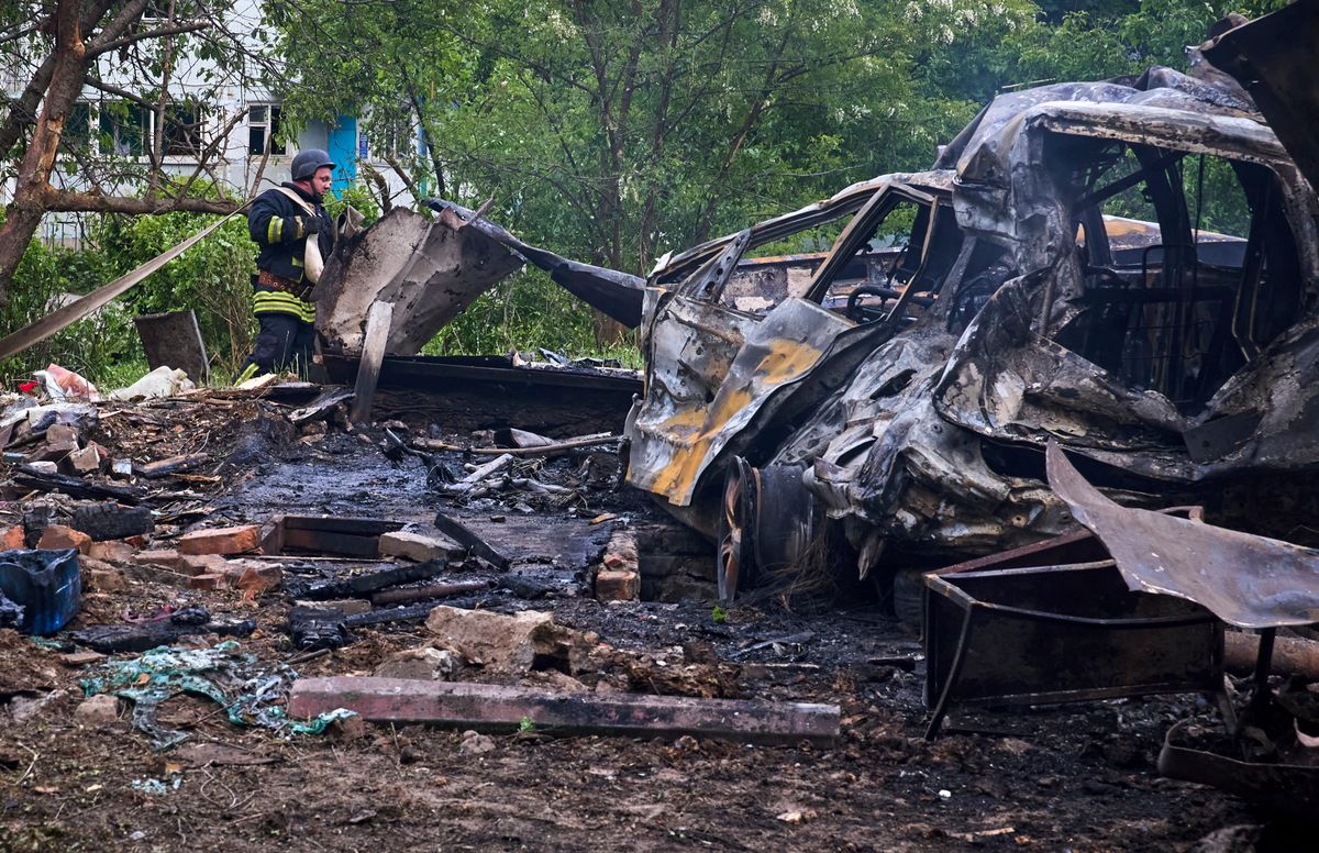 Kiégett autóroncs és törmelékek mellett mentő Harkivban 2024. május 14-én, miután orosz rakéta-és siklóbomba-támadás érte a kelet-ukrajnai város egyik lakónegyedét. (Fotó: MTI/EPA/Szergej Kozlov)