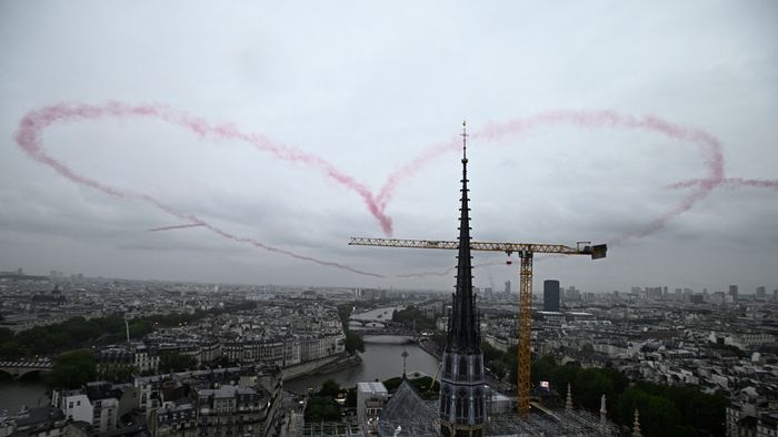 A heart made with red smoke by 4 planes floats in the air near Notre-Dame Cathedral during the opening ceremony of the Paris 2024 Olympic Games in Paris on July 26, 2024. (Photo by JULIEN DE ROSA / POOL / AFP)