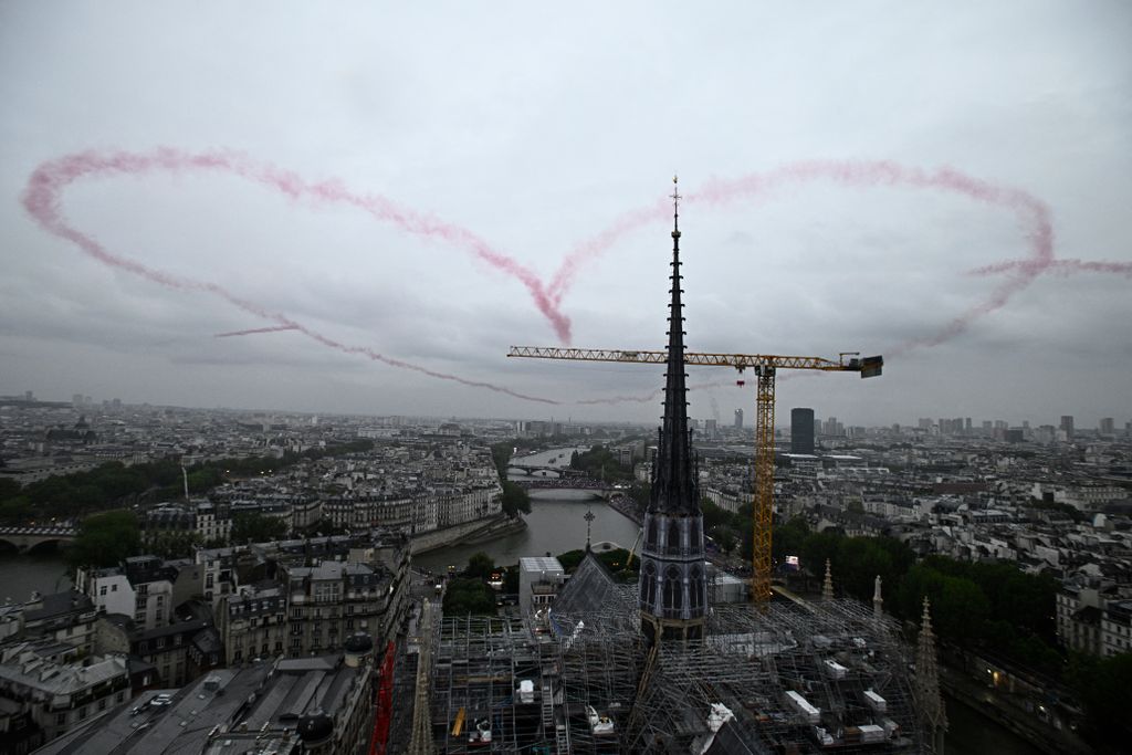 A heart made with red smoke by 4 planes floats in the air near Notre-Dame Cathedral during the opening ceremony of the Paris 2024 Olympic Games in Paris on July 26, 2024. (Photo by JULIEN DE ROSA / POOL / AFP)