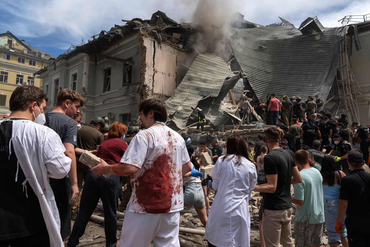 A mentőegységek tagjai, egészségügyi dolgozók és önkéntesek túlélőket keresnek egy légicsapásban találatot kapott gyermekkórház törmeléke közt Kijevben 2024. július 8-án. (Fotó: MTI/AP/Efrem Lukackij)