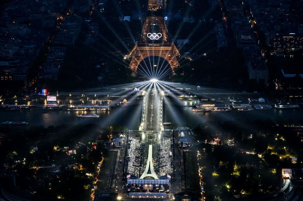 A photograph taken from an helicopter on July 26, 2024 shows an aerial view of the Eiffel Tower and the Olympics Rings lightened up during the opening ceremony of the Paris 2024 Olympic Games in Paris. (Photo by Lionel BONAVENTURE / POOL / AFP)