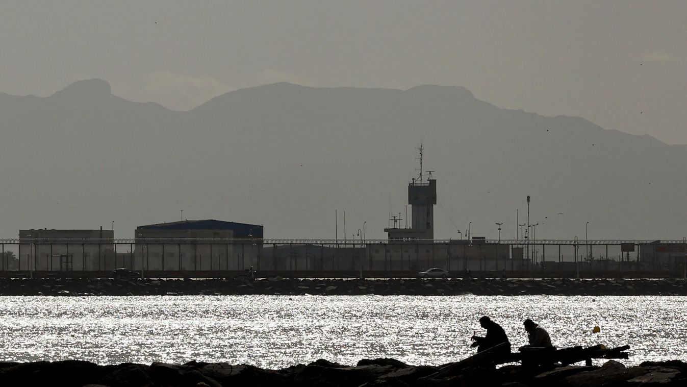 This picture taken on February 24, 2024 shows a view of the border fence separating Nador Beni Ansar Grand Port, Morocco (top) from Playa de la Hipica beach in Spain's North African Melilla enclave (Bottom). 23 migrants and asylum seekers died on June 24, 2022, after a crowd crush at the Melilla border fence in which Moroccan officers and Spanish Civil Guards were involved. Ceuta and Melilla, two Spanish territories on the northern Moroccan coast, are the European Union's only land borders on the African continent and are frequently the target of migrants hoping to reach mainland Europe. (Photo by OSCAR DEL POZO / AFP)