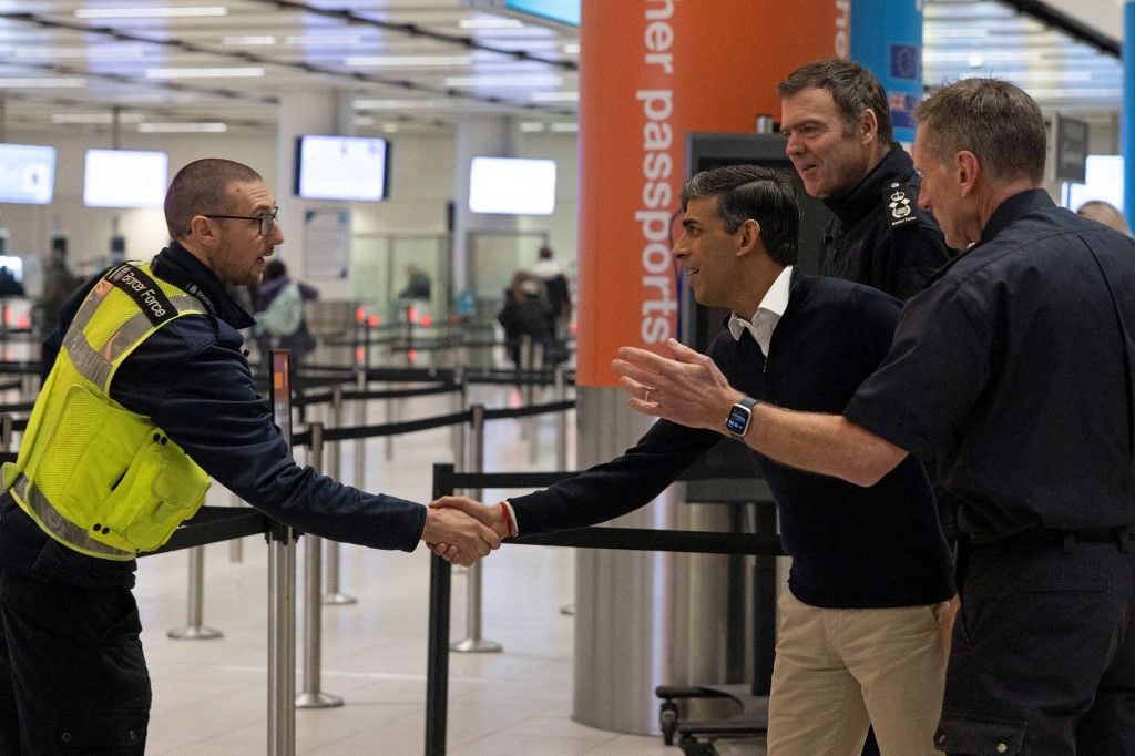 Rishi Sunak (C) brit miniszterelnök és a Belügyminisztérium határvédelmi főigazgatója, Phil Douglas (2R) beszél a határőri tisztekkel a Londontól délre fekvő Gatwick repülőtéren tett látogatása során 2024. január 18-án.