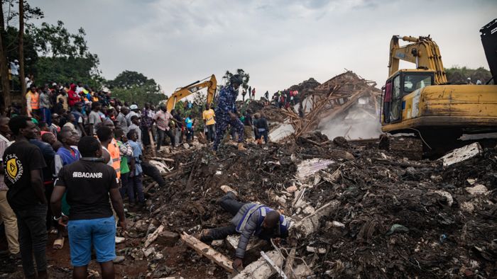 People look on as an excavator helps search for people trapped under debris after a landfill collapsed in Kampala on August 10, 2024. Eight people including two children were killed when mountains of garbage collapsed at a landfill in the Ugandan capital Kampala on August 10, the city authority said. (Photo by BADRU KATUMBA / AFP)
A man falls while running away from police officers securing the scene following a landfill collapse in Kampala on August 10, 2024. Eight people including two children were killed when mountains of garbage collapsed at a landfill in the Ugandan capital Kampala on August 10, the city authority said. (Photo by BADRU KATUMBA / AFP)