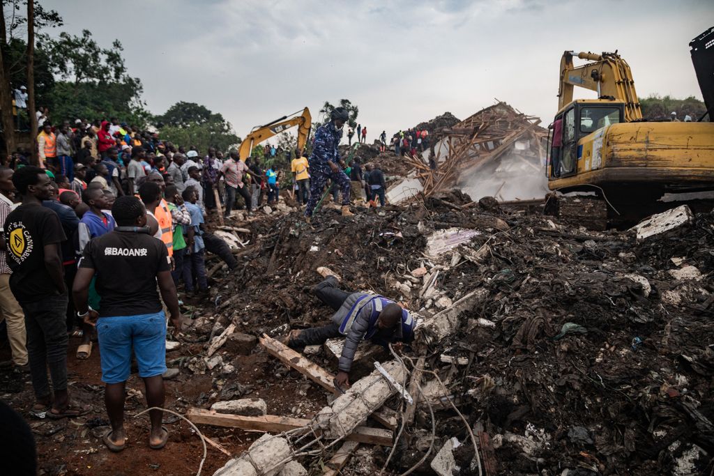 People look on as an excavator helps search for people trapped under debris after a landfill collapsed in Kampala on August 10, 2024. Eight people including two children were killed when mountains of garbage collapsed at a landfill in the Ugandan capital Kampala on August 10, the city authority said. (Photo by BADRU KATUMBA / AFP)
A man falls while running away from police officers securing the scene following a landfill collapse in Kampala on August 10, 2024. Eight people including two children were killed when mountains of garbage collapsed at a landfill in the Ugandan capital Kampala on August 10, the city authority said. (Photo by BADRU KATUMBA / AFP)