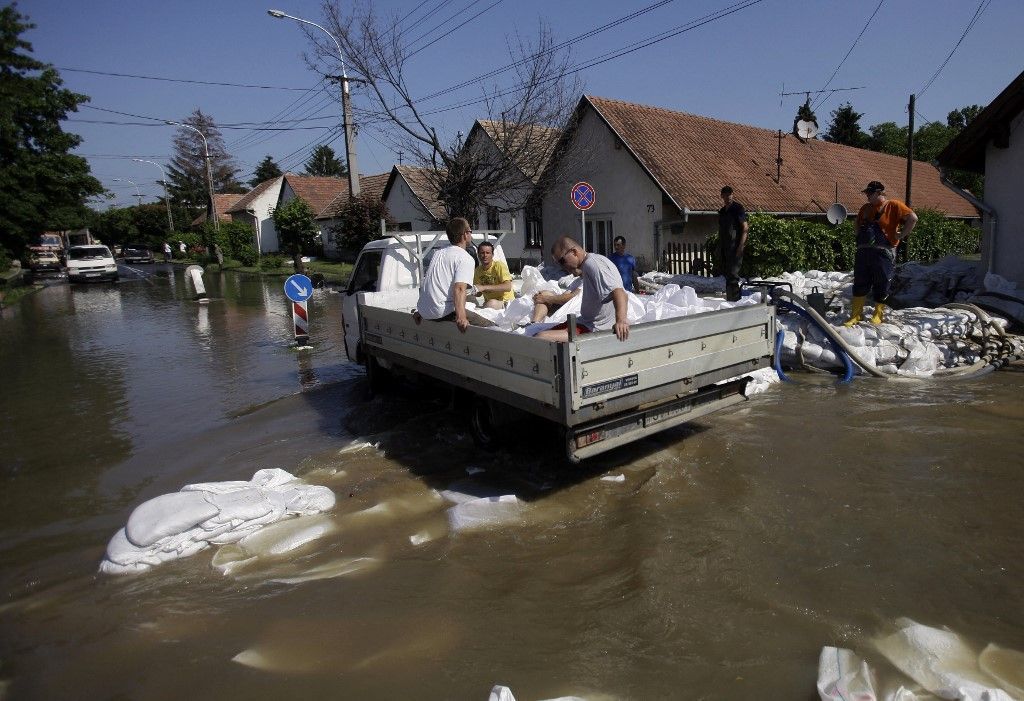 Helyi lakosok vízszivattyút használnak a beömlő víz ellen családi házuk előtt, a Duna árvize mellett Dunabogdányban, a Budapesttől mintegy 40 kilométerre északra fekvő településen 2013. június 9-én. Fotó: PETER KOHALMI / AFP