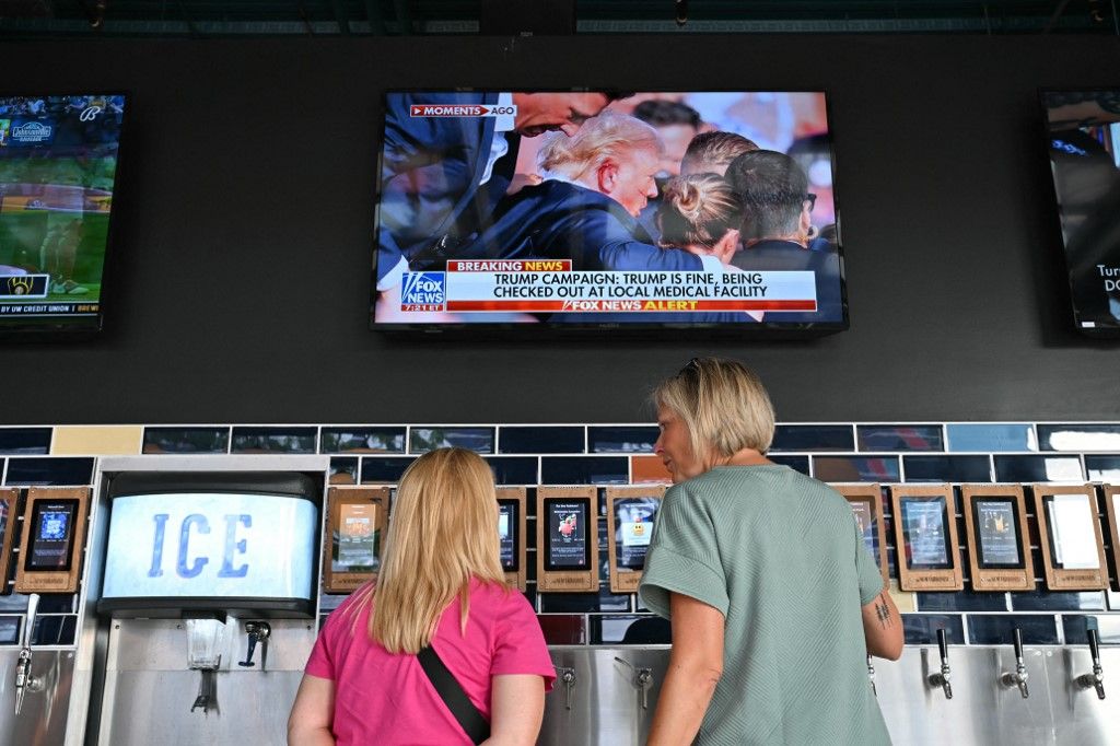 Emberek nézik a híreket a televízióban, miután meghallották, hogy Donald Trumpot ellen merényletet követtek el a pennsylvaniai nagygyűlésén