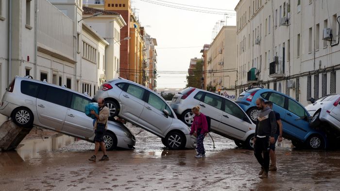 Residents walk past piled up cars following deadly floods in Valencia's De La Torre neighbourhood, south of Valencia, eastern Spain, on October 30, 2024. Floods triggered by torrential rains in Spain's eastern Valencia region has left at least 70 people dead, rescue services said on October 30. (Photo by Manaure QUINTERO / AFP)