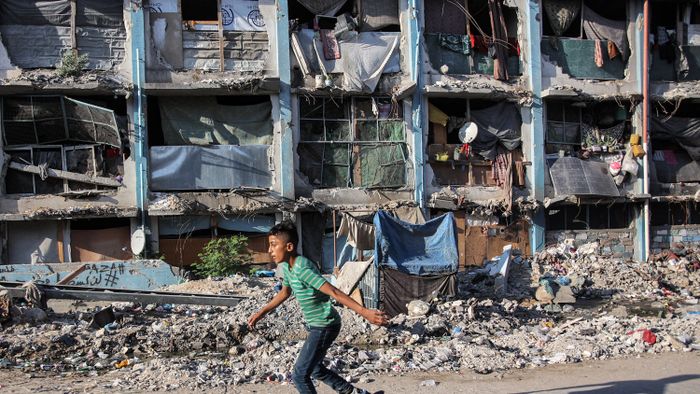 A boy roller-blades past a destroyed building at a camp sheltering people displaced by conflict in Jabalia in the northern Gaza Strip on September 8, 2024 amid the ongoing war in the Palestinian territory between Israel and Hamas. (Photo by Omar AL-QATTAA / AFP)