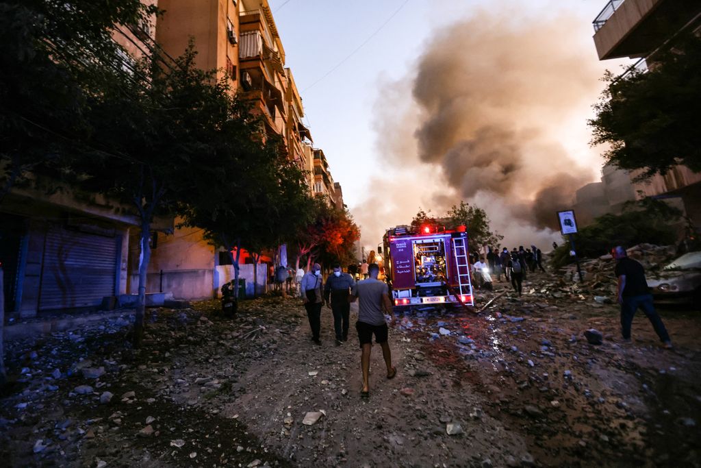 People and a fire truck rush to the scene of an Israeli air strike in the Haret Hreik neighbourhood of Beirut's southern suburbs on September 27, 2024. A source close to Hezbollah said the massive Israeli strikes on Beirut's southern suburbs flattened six buildings. (Photo by Ibrahim AMRO / AFP)