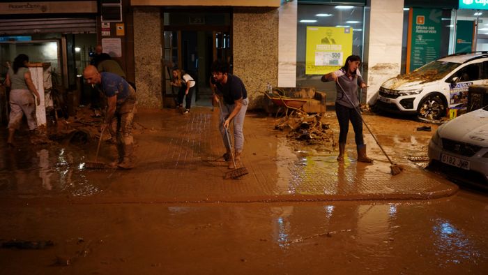 Residents clean the pavement following deadly floods in Valencia's De La Torre neighbourhood, south of Valencia, eastern Spain, on October 30, 2024. Floods triggered by torrential rains in Spain's eastern Valencia region has left at least 70 people dead, rescue services said on October 30. (Photo by Manaure Quintero / AFP)