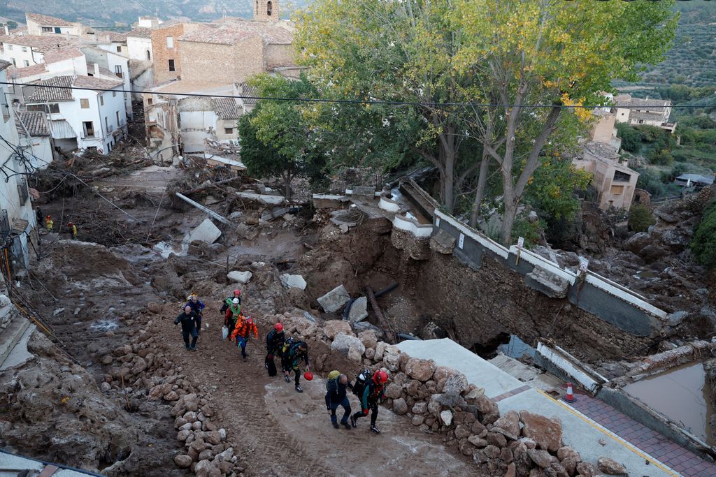 Emergency services staff members walk in a street devastated following floods in Letur, southwest of Valencia, eastern Spain, on October 30, 2024. Floods triggered by torrential rains in Spain's eastern Valencia region has left at least 70 people dead, rescue services said on October 30. (Photo by OSCAR DEL POZO / AFP)