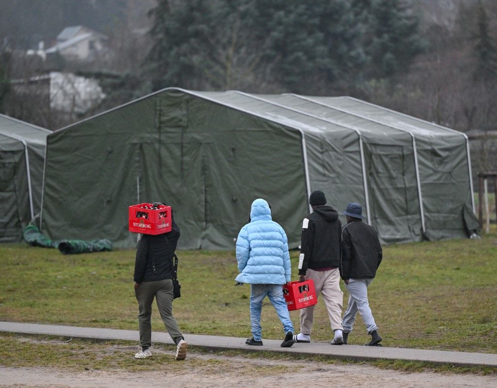 A migránsok sörrekeszeket visznek a szálláshelyükre a Brandenburgi Menedékkérők Központi Befogadó Központjában (ZABH), Eisenhüttenstadtban