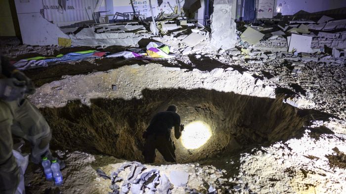 Members of Israel's Home Front Command and police forces inspect a crater left by an exploded projectile at a heavily-damaged school building in Israel's southern city of Gedera on October 1, 2024, after Iran launched a barrage of missiles at Israel in response to the killings of Lebanese Hezbollah leader Nasrallah and other Iran-backed militants. Reports said Iran fired between 150 and 200 missiles in the attack, the country's second on Israel after a missile and drone attack in April in response to a deadly Israeli air strike on the Iranian consulate in Damascus. (Photo by Menahem KAHANA / AFP)